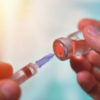 Closeup of vaccine bottle with syringe and needle for immunization on vintage medical background, medicine and drug concept