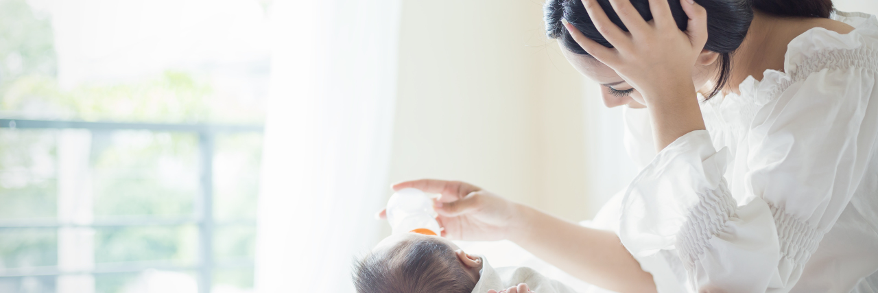 Tips for Navigating Postpartum Mental Health a mom is feeding a baby a bottle while laying on the bed