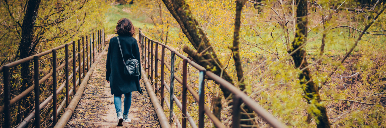 An Apology Letter to the Sick Friend I Lost a woman walking over a bridge in a park