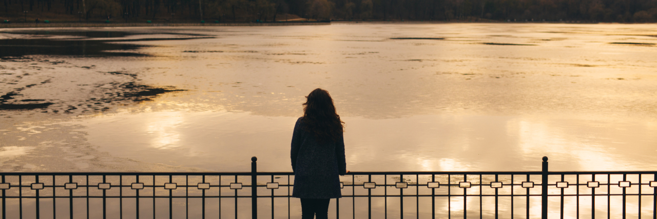 My Feelings About Having a Chronic Illness Are Valid Woman looking out on the water at sunset.