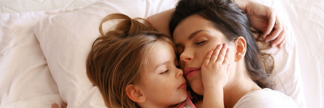 How My Little Girl Tries to Cure Mama's Migraine a little girl is comforting her daughter as they lay next to each other