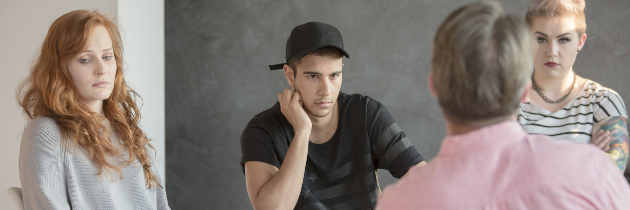 Group Therapy as an Introvert With Depression and Anxiety photo of group therapy session with multiple young people talking to older male therapist