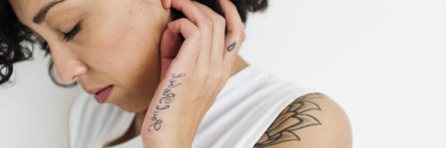 A profile of a woman with tattoos on her hand.
