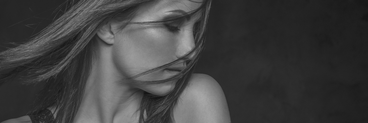 Reconnecting With My Sexuality as Someone With Depression a woman with her eyes closed and hair falling over her face. Her undergarment falling off her shoulder