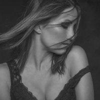 a woman with her eyes closed and hair falling over her face. Her undergarment falling off her shoulder
