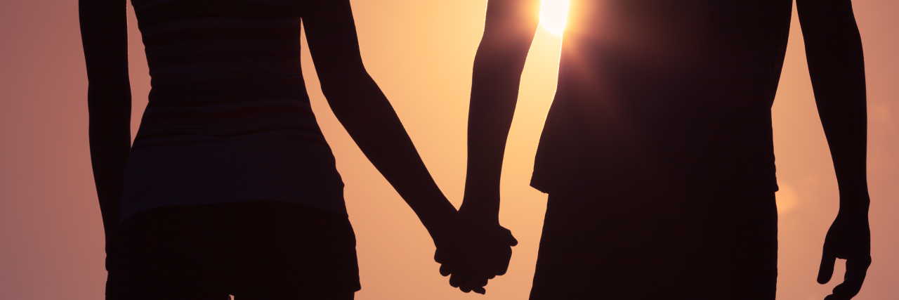 Couple holding hands at sunset.