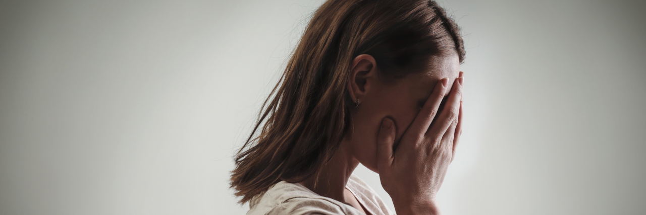 How to Cope With Emotional Triggering and Chronic Illness woman covering face with her hands, side view