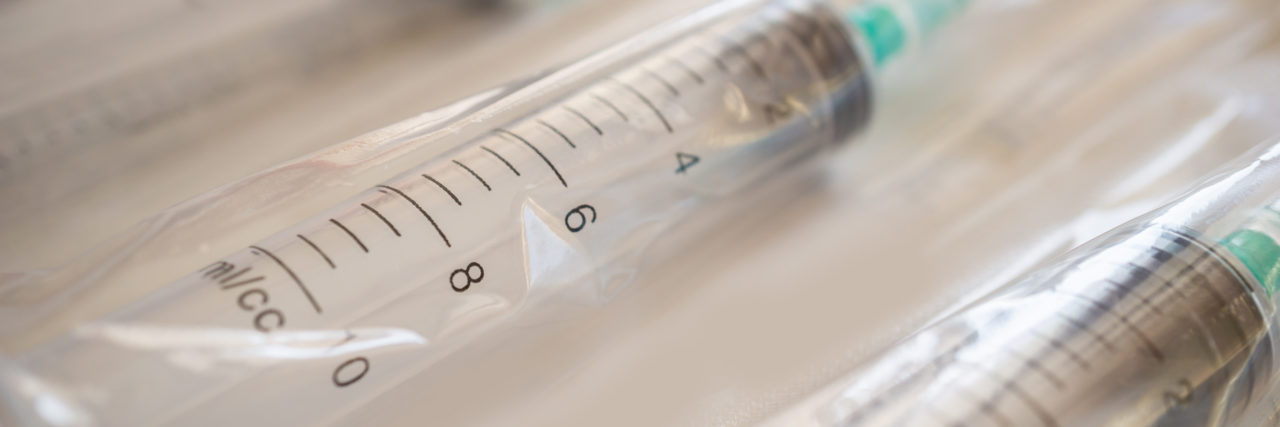 Using Fun Band-Aids to Cope With Rheumatoid Arthritis Injections Disposable plastic syringes with needles in package.