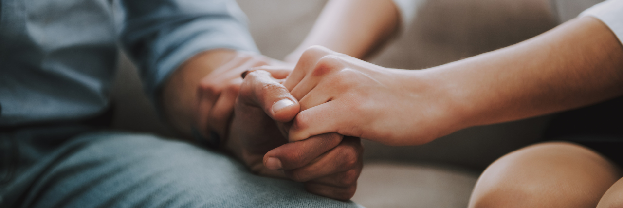 Man and woman holding hands on the couch.