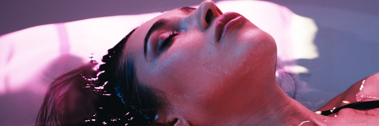 How a Float Tank Gave Me Control Over My Migraines a woman is floating in a spa or pool