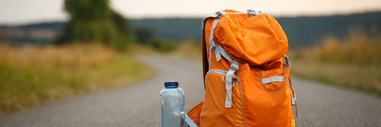 Orange backpack and water bottle on a trail in the country.