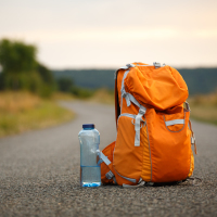 Orange backpack and water bottle on a trail in the country.