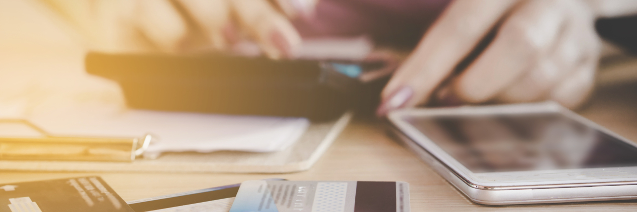 Ways to Fight Health Insurance and Incorrect Hospital Bills woman on calculator with credit cards on her desk, focus on her hands