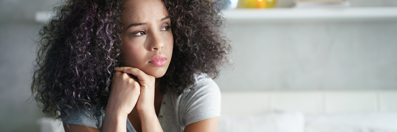 Reactive Attachment Disorder in Adults Ruins Relationships Lonely young woman sitting on bed. Depressed girl at home, looking away with sad expression.