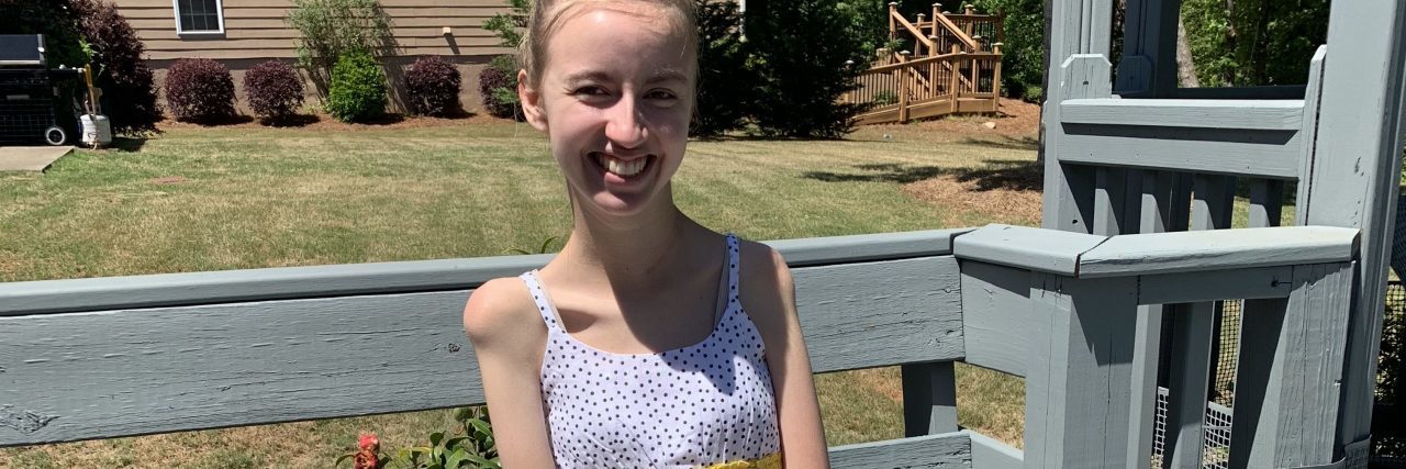 Sarah wearing shorts and a yellow tank top while sitting on a bench.