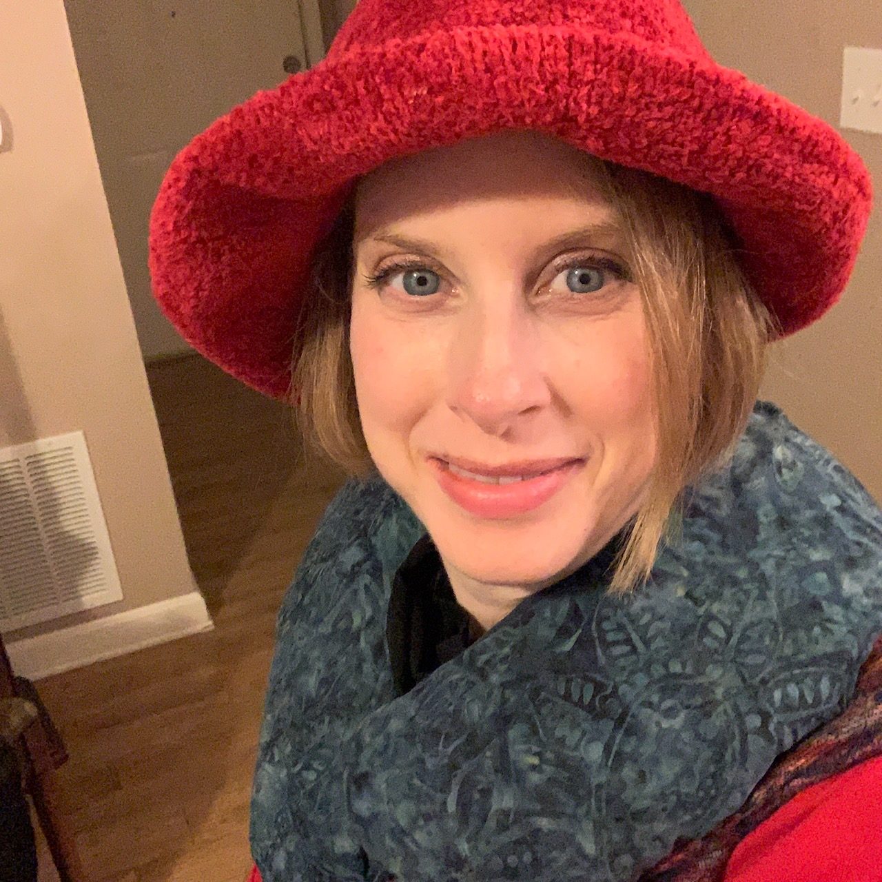 Jenny wearing a red hat and gray neck wrap.