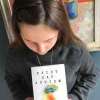 Girl holding a copy of "Daisy Has Autism"