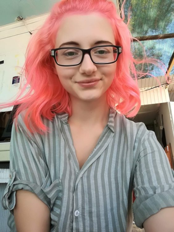 woman with bright pink hair smiling at the camera