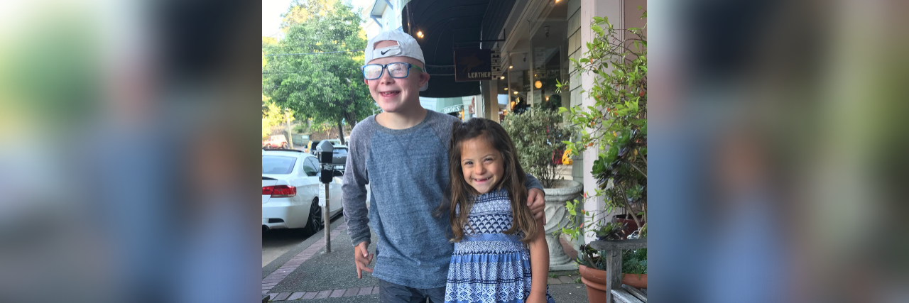 Why I Choose to Parent Two Children With Down Syndrome Brother and sister hugging and smiling at camera. They both have Down syndrome.