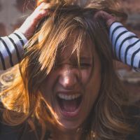 photo of woman with hands in hair screaming