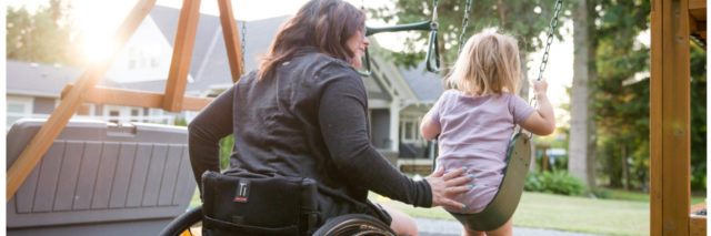 Woman in wheelchair pushing her child on a swing.