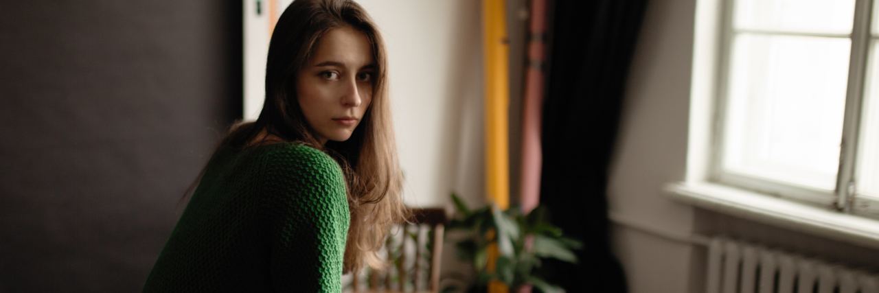 photo of sad looking girl on chair in empty room