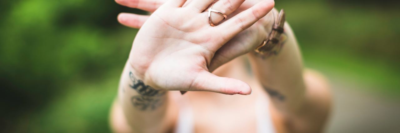 Why Forced Positive Thinking Is a Problem for Mental Health photo of woman holding out hands which cover view of her face