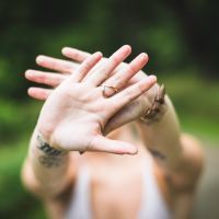 photo of woman holding out hands which cover view of her face