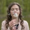photo of woman blowing dandelion with eyes closed