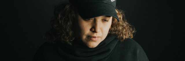 photo of latina woman wearing baseball cap and looking down in sadness