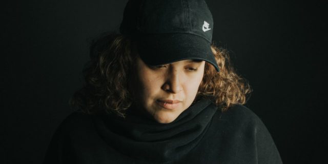 photo of latina woman wearing baseball cap and looking down in sadness
