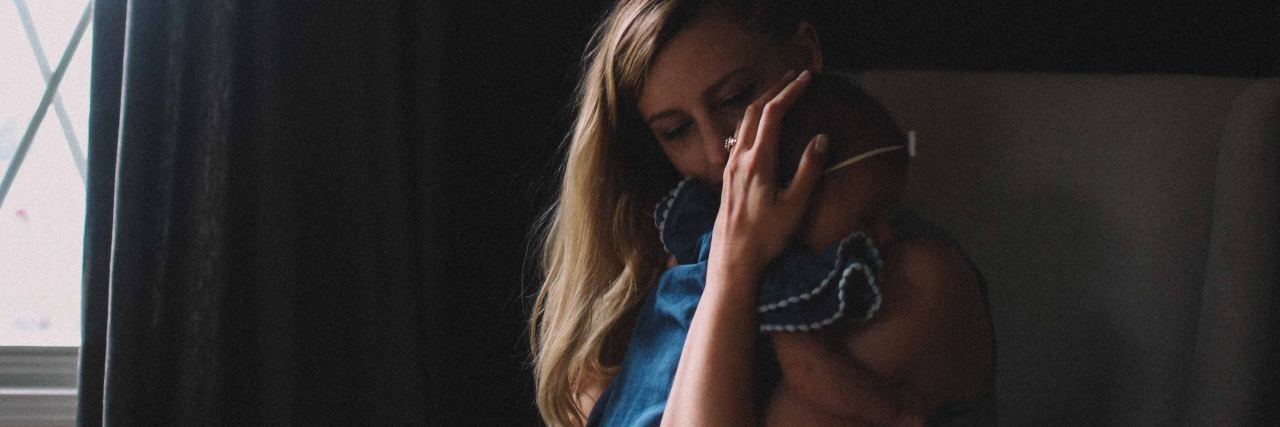 Loved Ones Are Affected by Postpartum Disorders Too photo of woman holding baby close by window