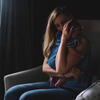 photo of woman holding baby close by window