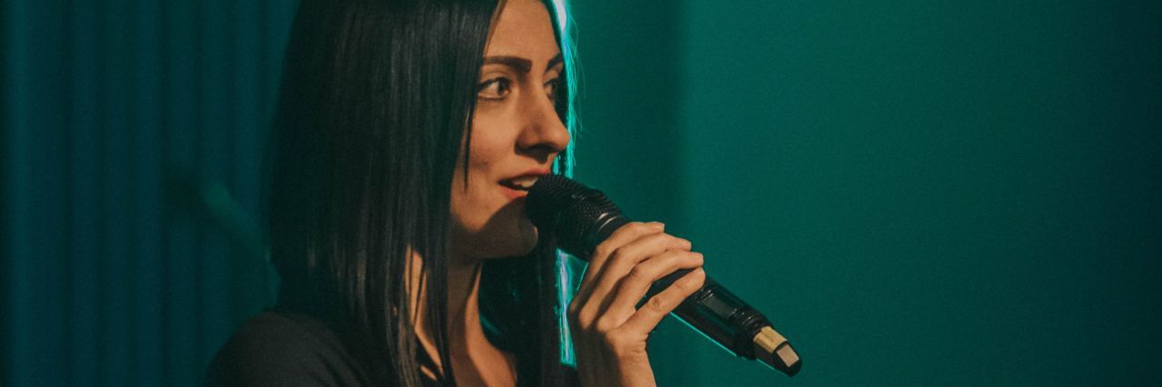 Why I Love Public Speaking, but Struggle With Social Anxiety photo of young woman on stage holding microphone