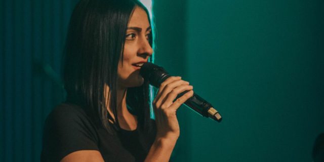 Why I Love Public Speaking, but Struggle With Social Anxiety photo of young woman on stage holding microphone