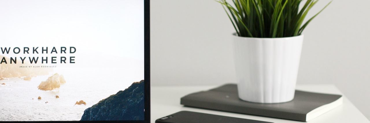 Remote Jobs for People With Disabilities and Chronic Illness Open laptop on a desk with a mouse and plant on a notebook