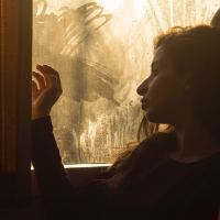 photo of bored tired looking woman on train or bus looking out of dirty window