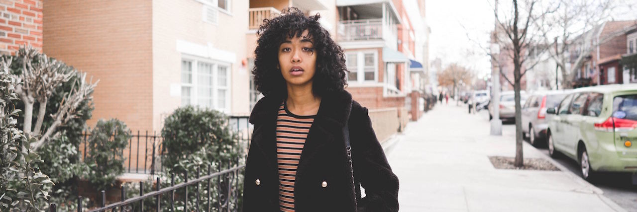 What It's Like In a Psychiatric Hospital A man wearing a dark coat, standing outside an apartment building