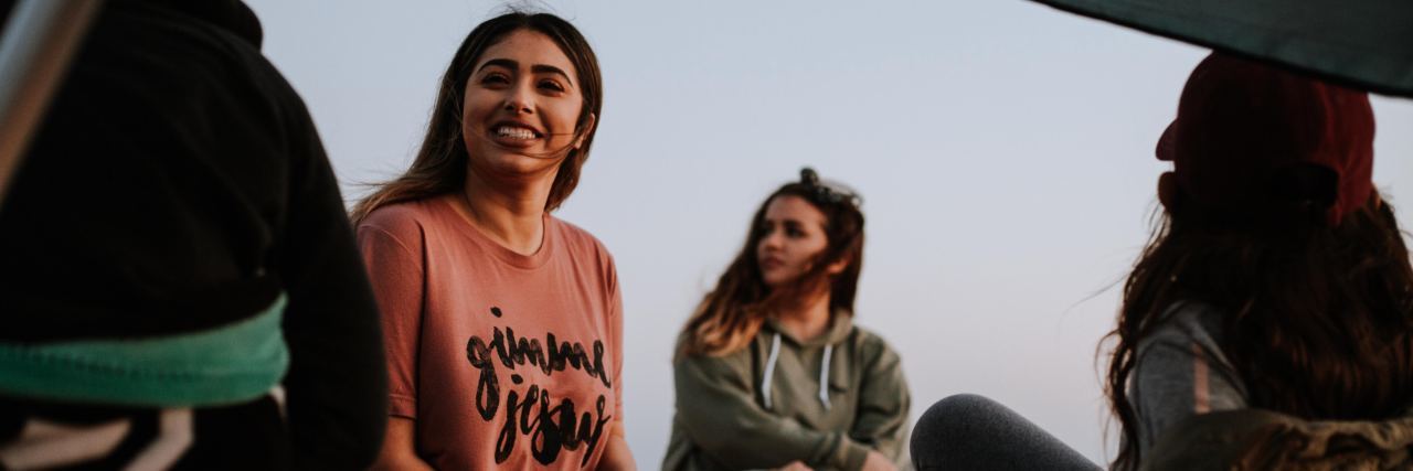 Why Someone With Social Anxiety Might Talk a Lot photo of group of young people sitting around at sunset and chatting