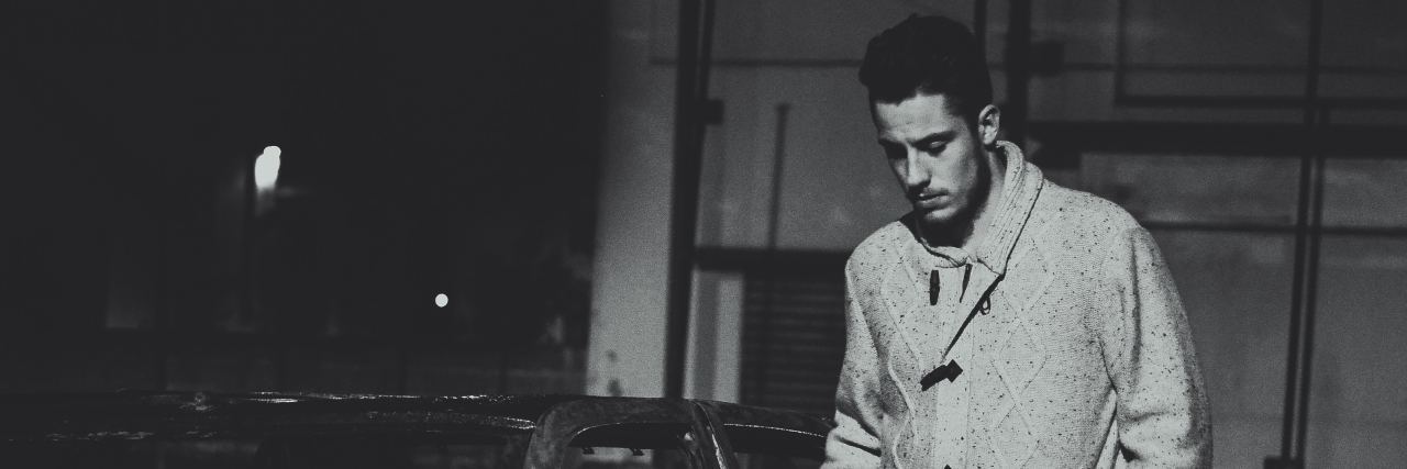What Is an 'Anxious Overfunctioner?' black and white photo of man standing next to burned car