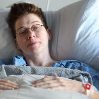 photo of hospital patient in bed looking at camera and smiling