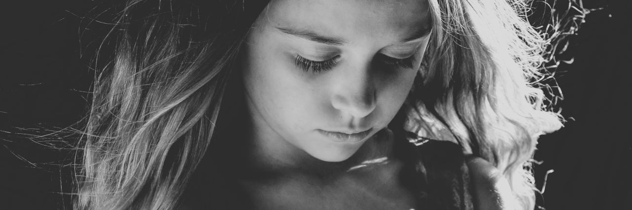 black and white photo of young girl looking down sad