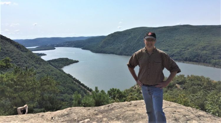 man standing on rock with view of river and valley