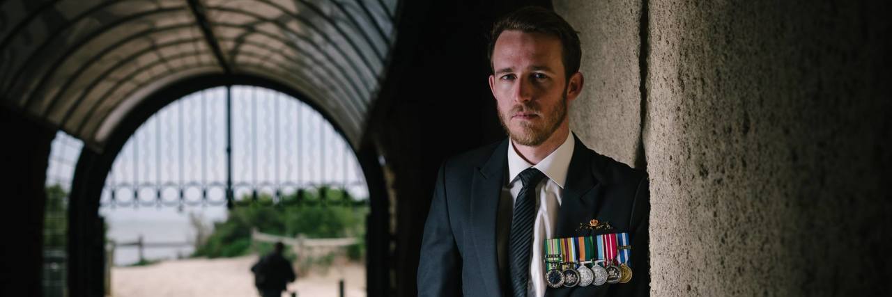 The Problem With How the Military Treats Men's Mental Health the author standing in a shadowy corridor wearing his military uniform