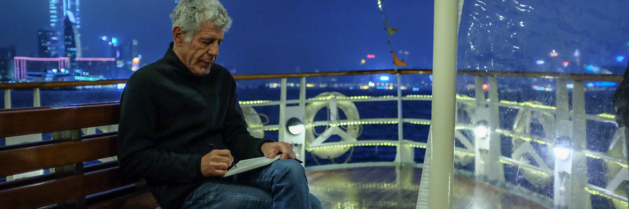 photo of anthony bourdain sitting on a boat, writing