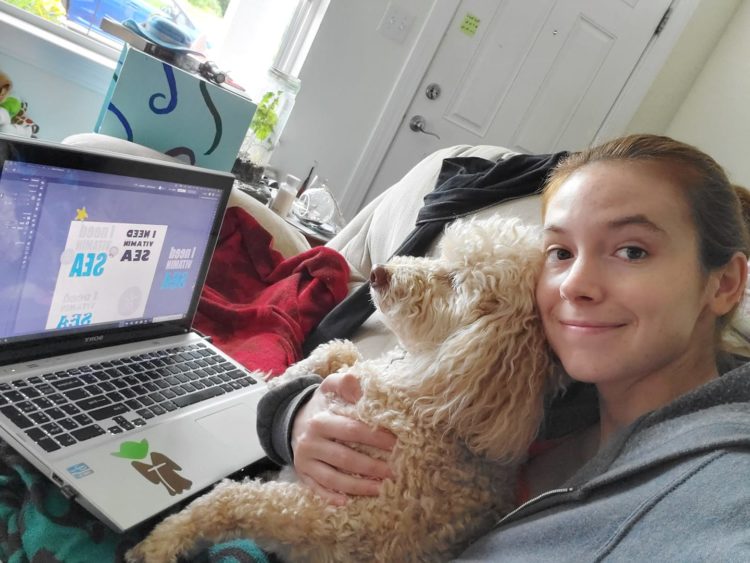 woman holding dog while working on laptop