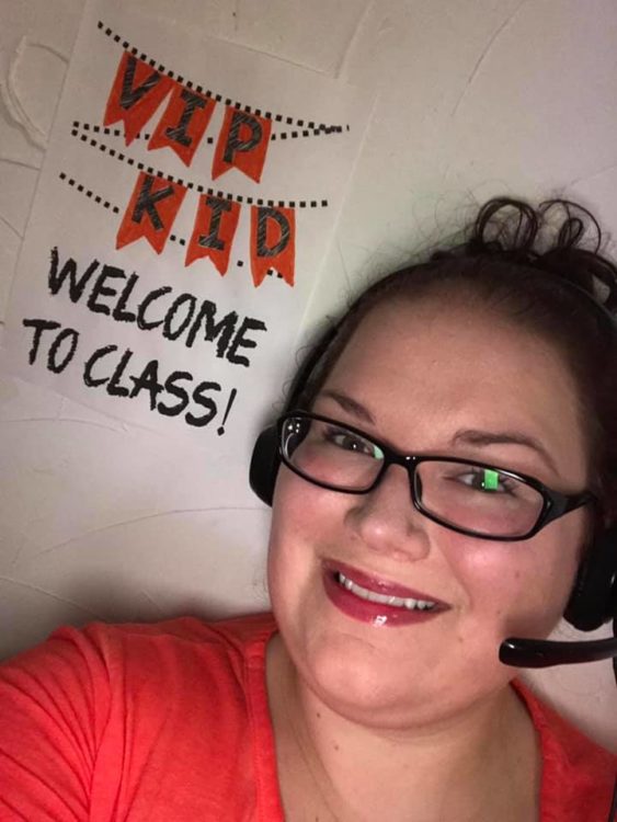 woman with headset and welcome to class sign