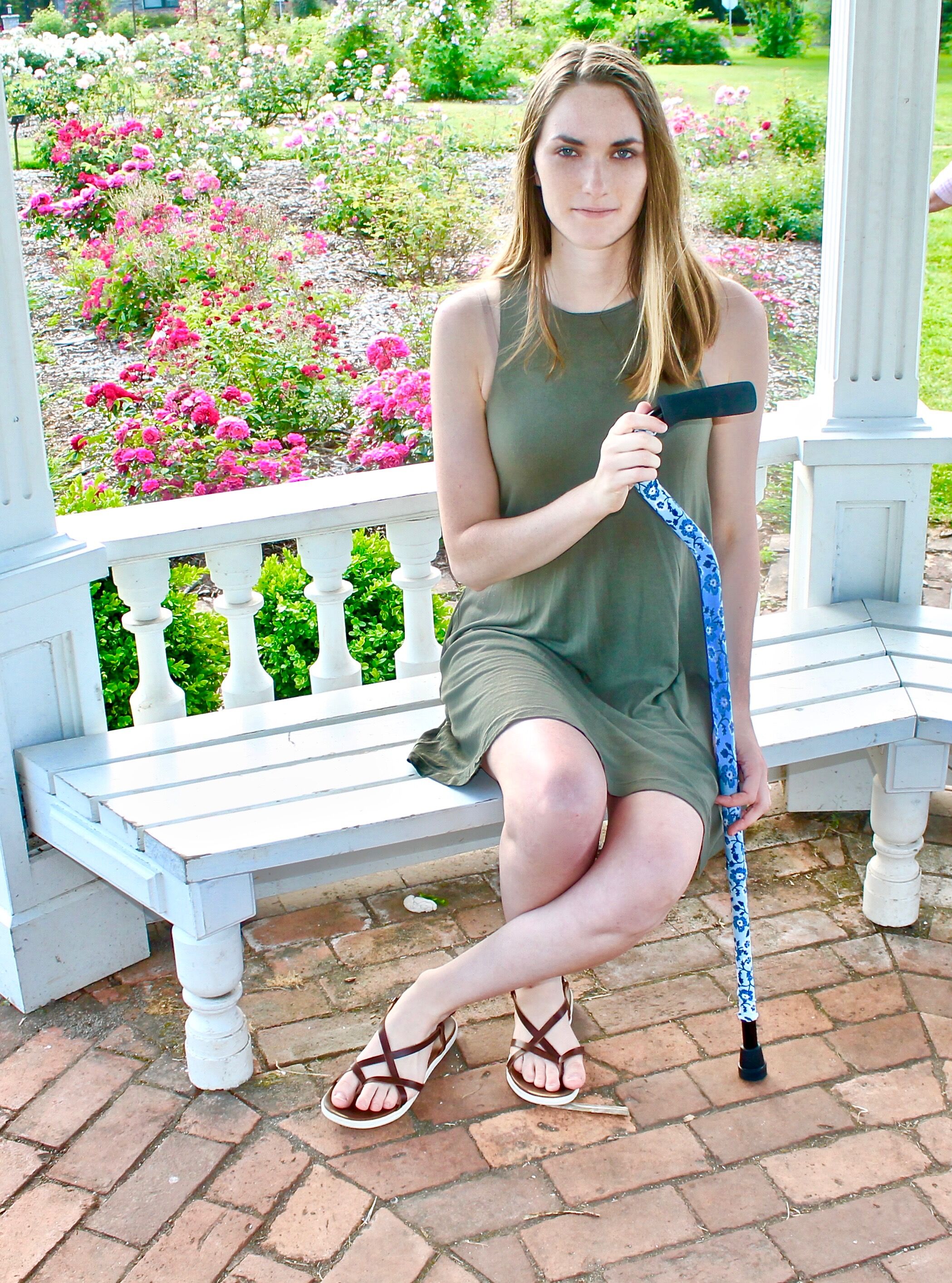 April sitting on a garden bench with her cane.
