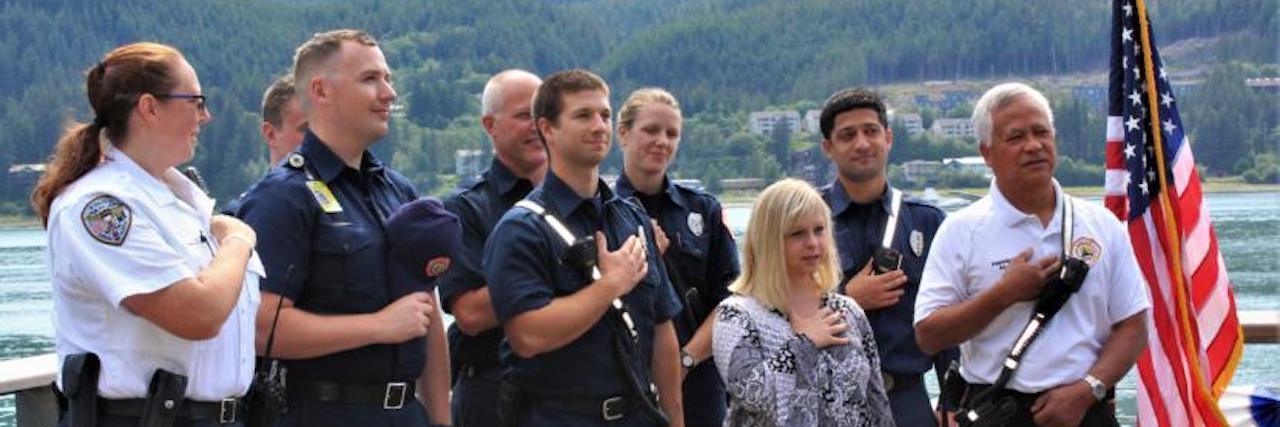 Ashley Deramus and police officers with hand over heart for National Anthem