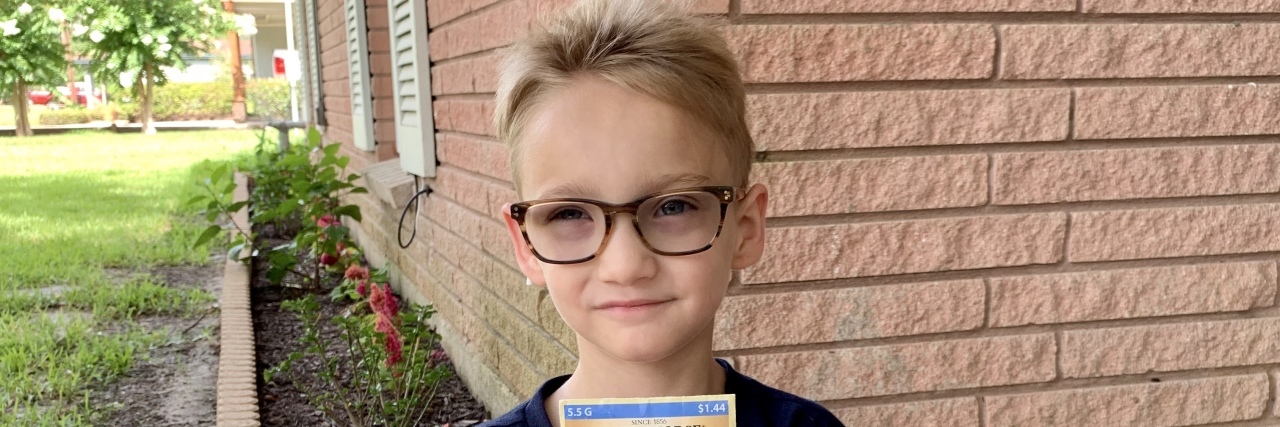 My Child With a Disability Is Going to Kindergarten Little boy sitting criss crossed holding a bag of sunflower seeds.